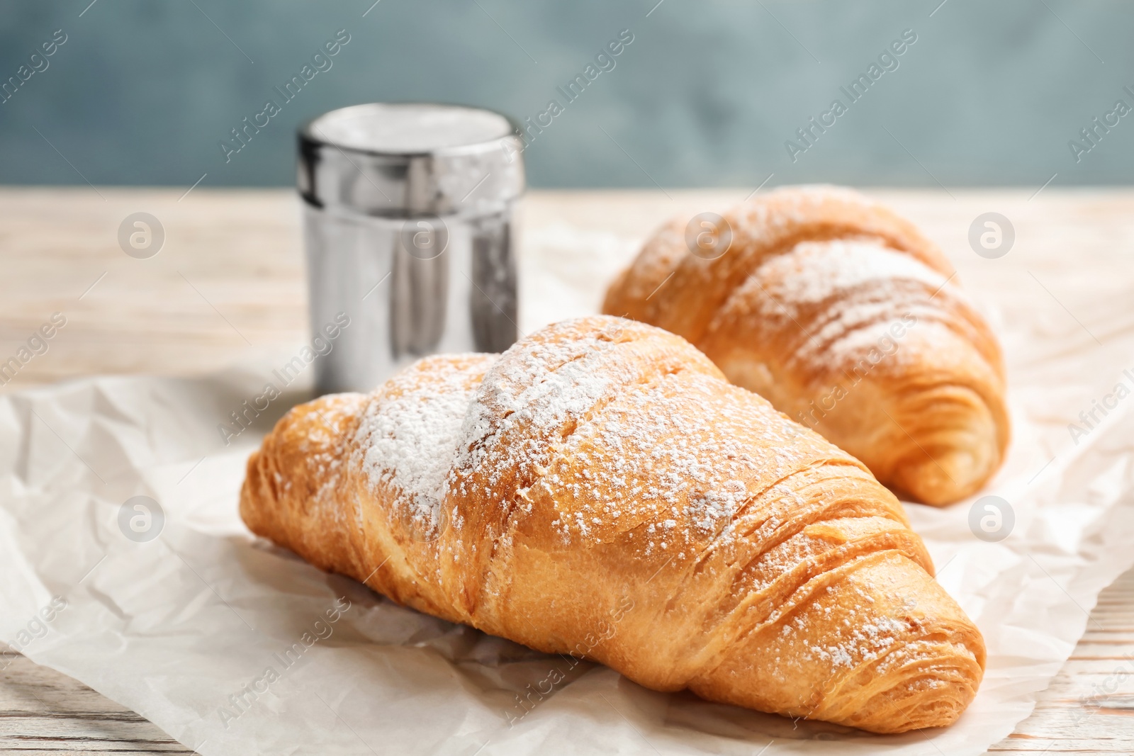 Photo of Tasty croissants with sugar powder on table