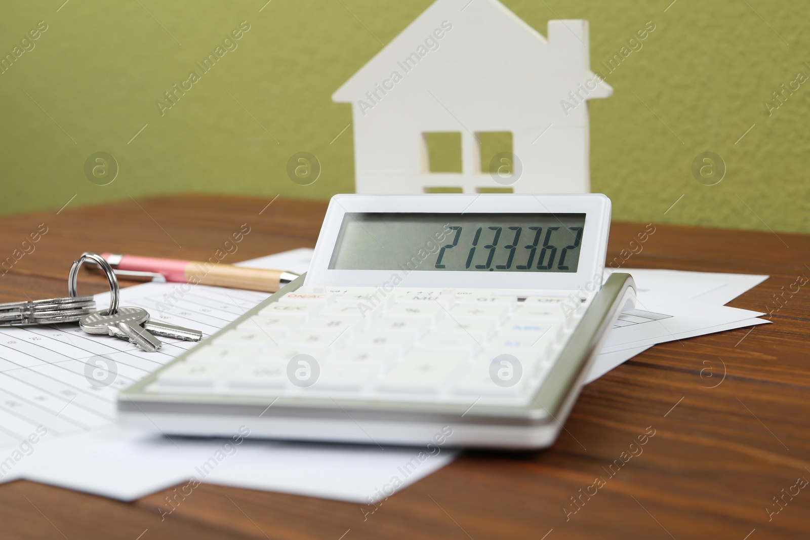 Photo of Calculator, house model, keys and documents on wooden table. Real estate agent's workplace