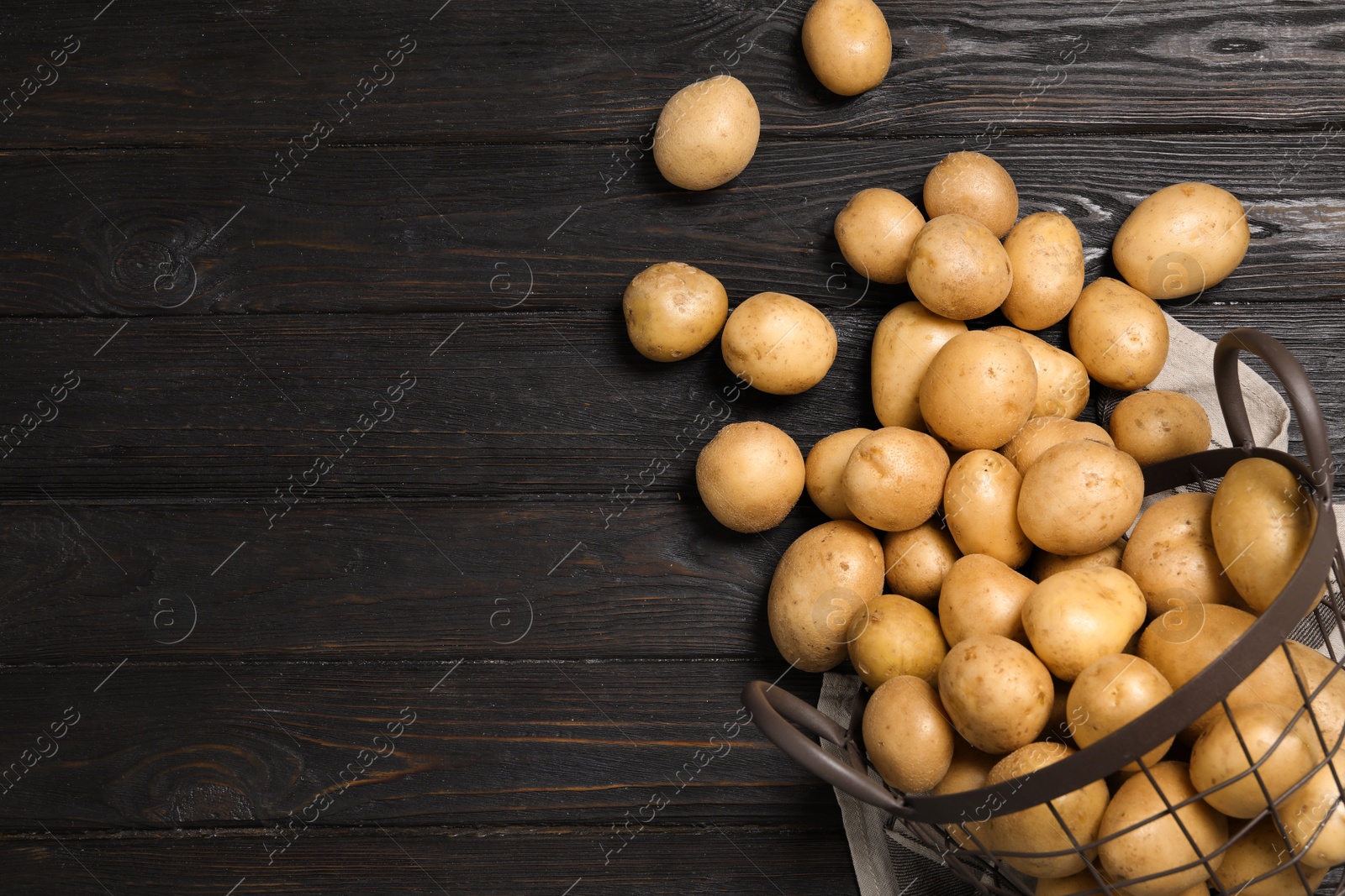 Photo of Raw fresh organic potatoes on black wooden background, top view. Space for text