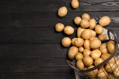 Photo of Raw fresh organic potatoes on black wooden background, top view. Space for text