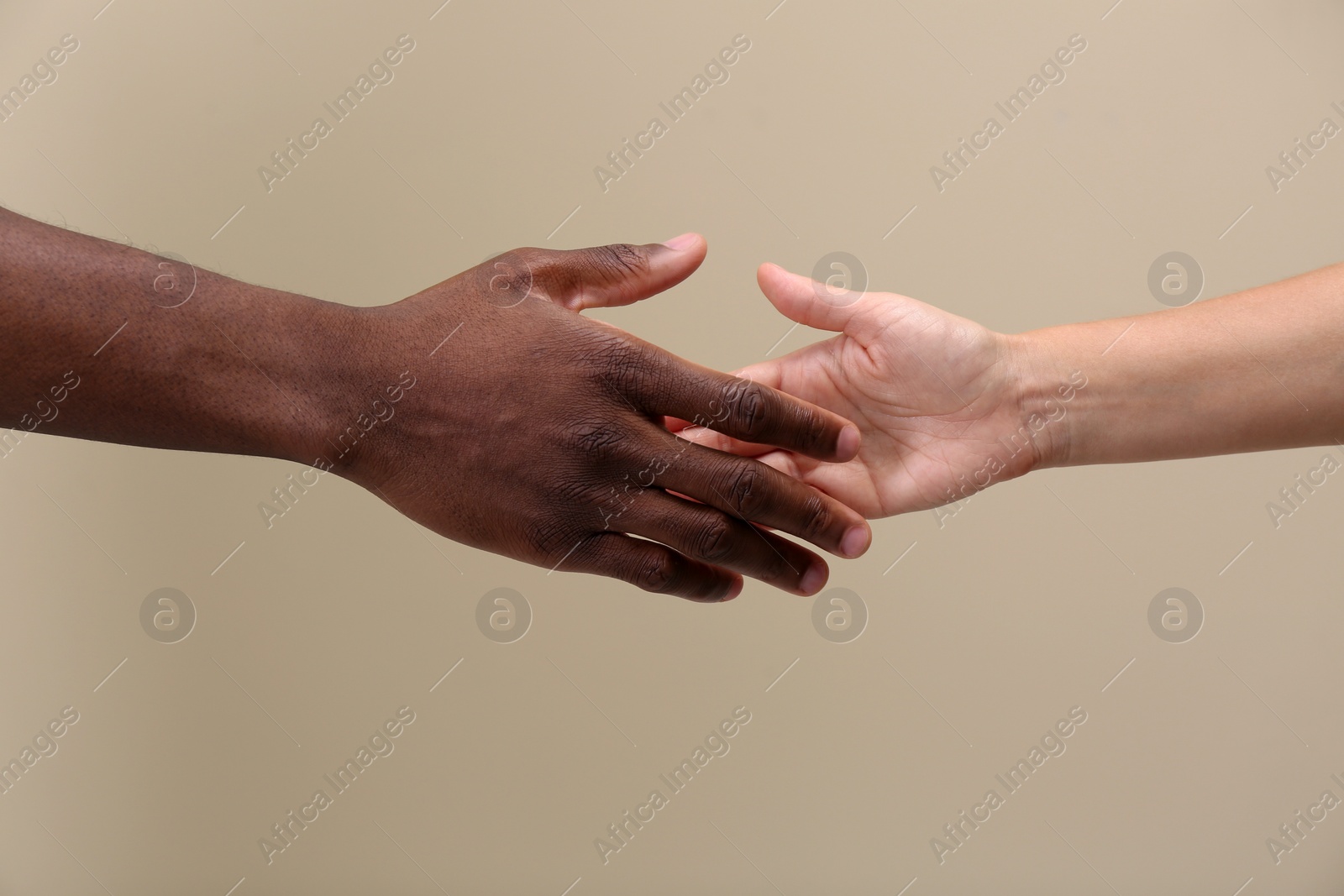 Photo of Woman and African American man shaking hands on beige background, closeup