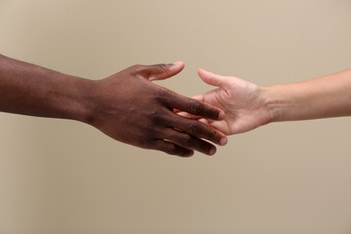 Photo of Woman and African American man shaking hands on beige background, closeup
