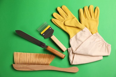 Photo of Beekeeping tools on green background, flat lay