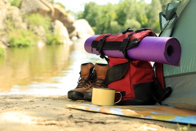 Photo of Modern camping tent and equipment on riverbank. Space for text