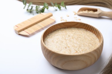 Homemade hair mask, oatmeal and comb on white background