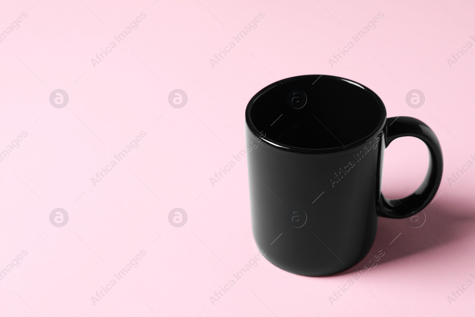 Black ceramic mug on pink background. Space for text Photo of Black ceramic mug on pink background. Space for text