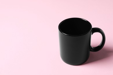 Photo of Black ceramic mug on pink background. Space for text