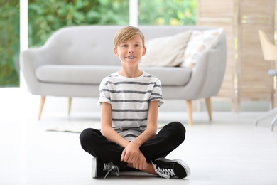 Portrait of young boy sitting on floor in living room