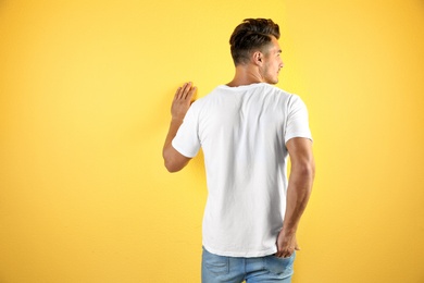 Photo of Young man in t-shirt on color background. Mockup for design