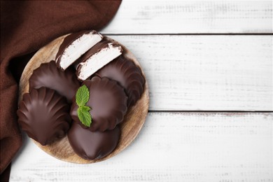 Photo of Delicious chocolate covered marshmallows with mint on white wooden table, flat lay. Space for text