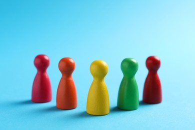 Photo of Colorful pawns on light blue background, closeup. Social inclusion concept