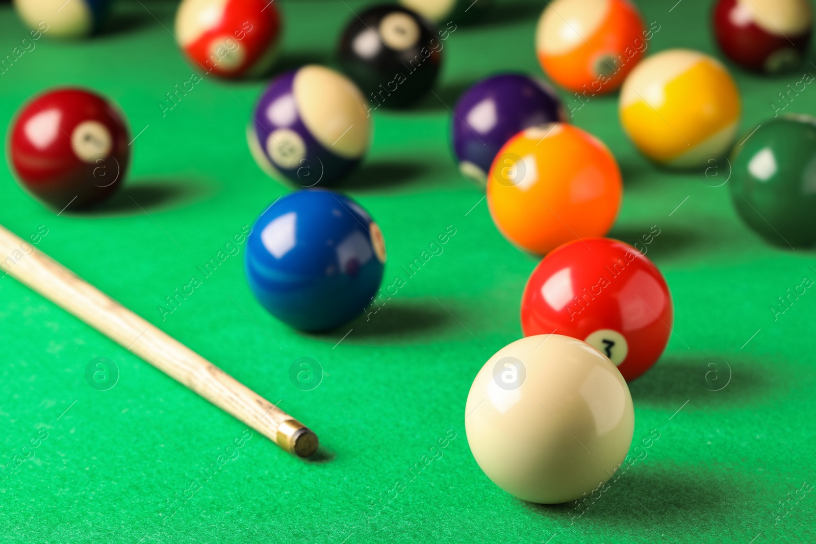 Photo of Many colorful billiard balls and cue on green table