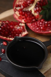 Photo of Tasty pomegranate sauce in bowl and fruit on table, closeup