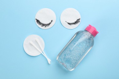 Photo of Dirty cotton pads, swabs and micellar cleansing water on light blue background, flat lay