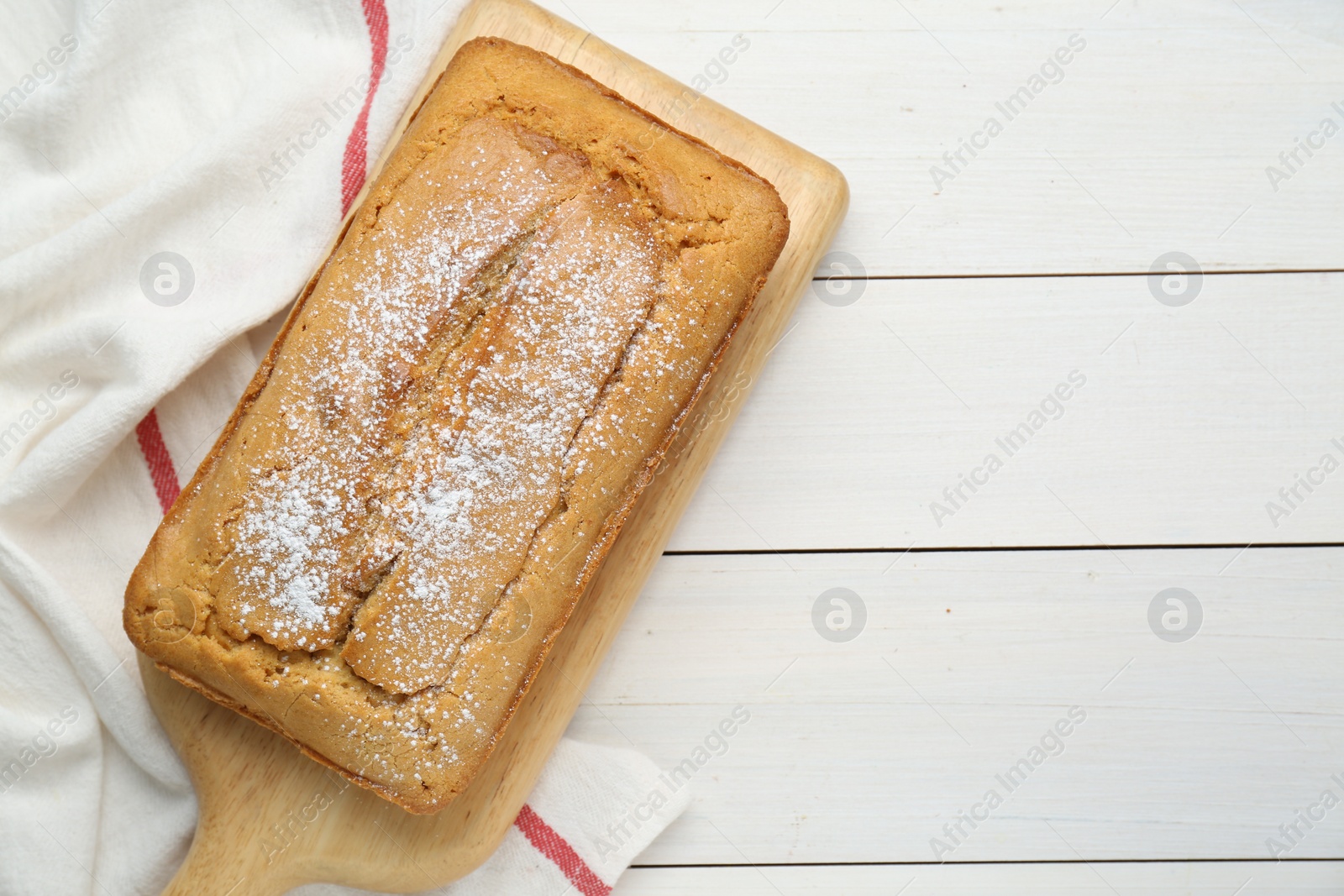 Photo of Delicious homemade yogurt cake with powdered sugar on white wooden table, top view. Space for text