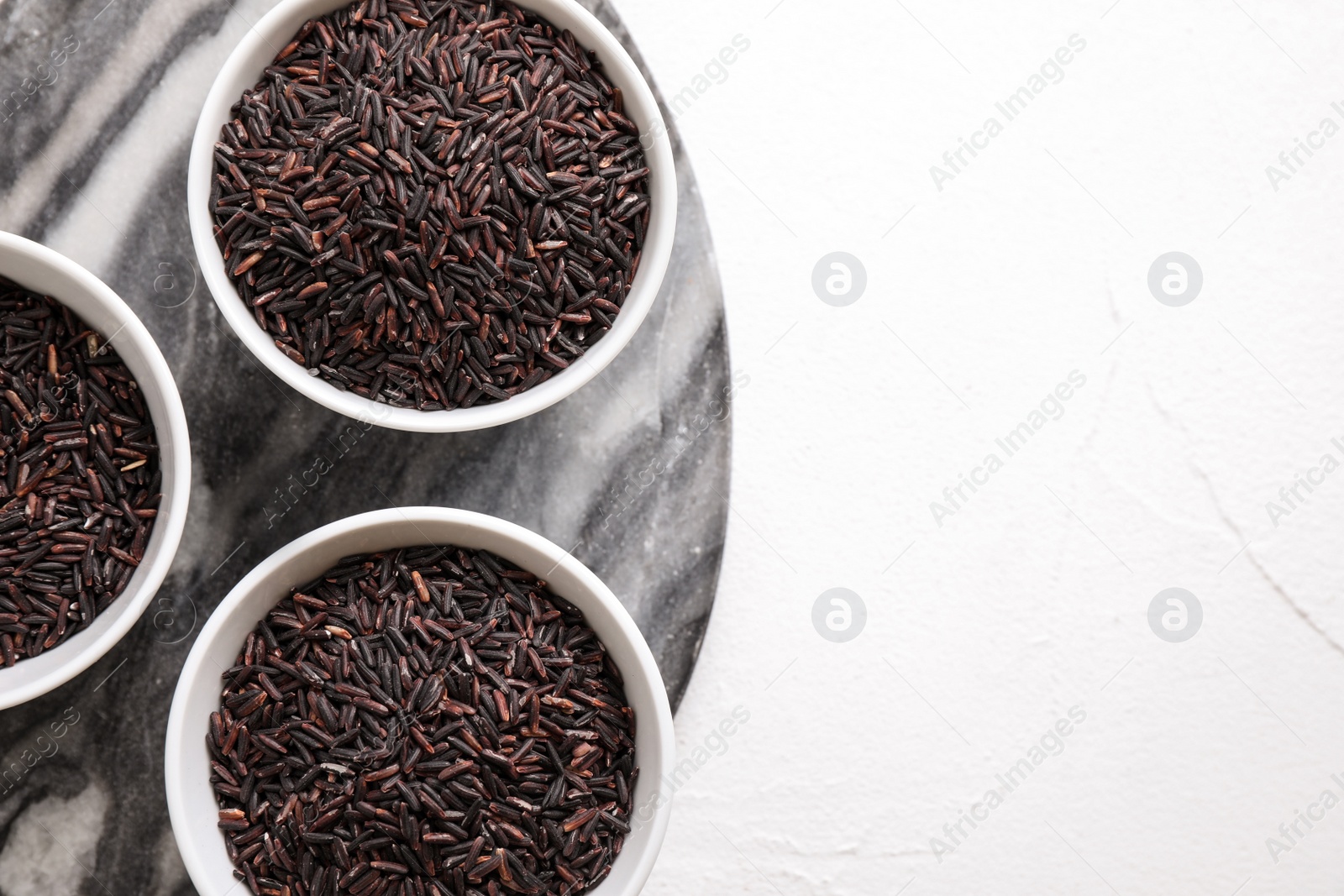 Photo of Brown rice on white table, flat lay. Space for text