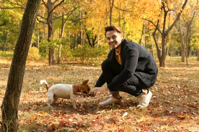 Photo of Young handsome man with his pet in park. Autumn walk