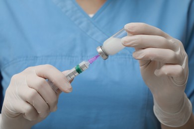 Photo of Doctor filling syringe with hepatitis vaccine from glass vial, closeup