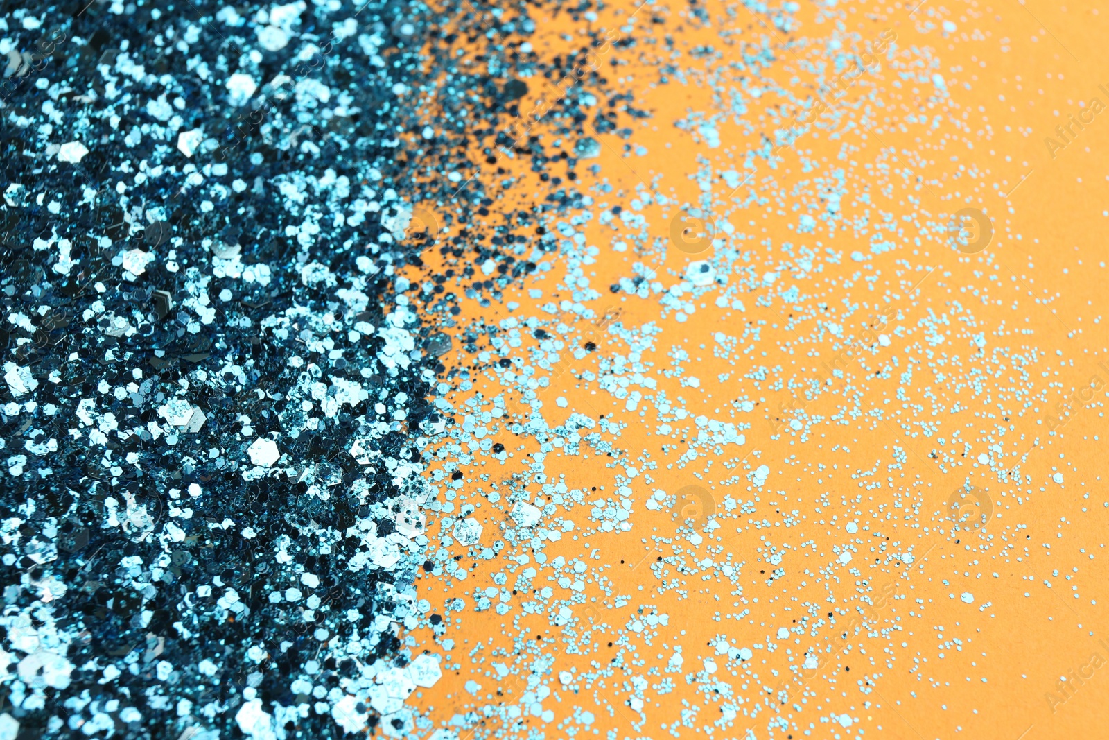 Photo of Shiny bright light blue glitter on pale orange background