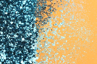 Photo of Shiny bright light blue glitter on pale orange background