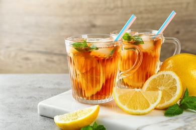 Cups of refreshing iced tea on table against wooden background