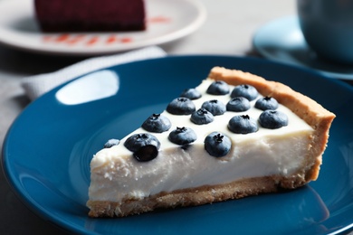 Plate with piece of tasty blueberry cake on table