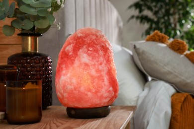 Beautiful Himalayan salt lamp on wooden nightstand in bedroom