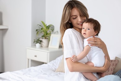 Photo of Mother hugging her cute little baby in bedroom, space for text