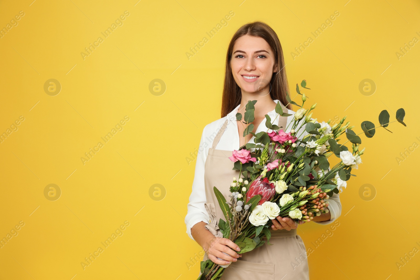 Photo of Florist with beautiful bouquet on yellow background, space for text