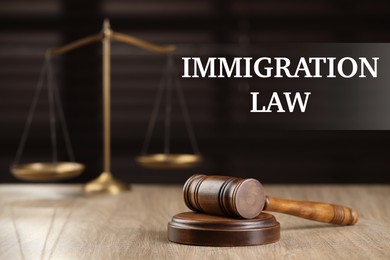Immigration law. Wooden gavel and scales of justice on table, selective focus