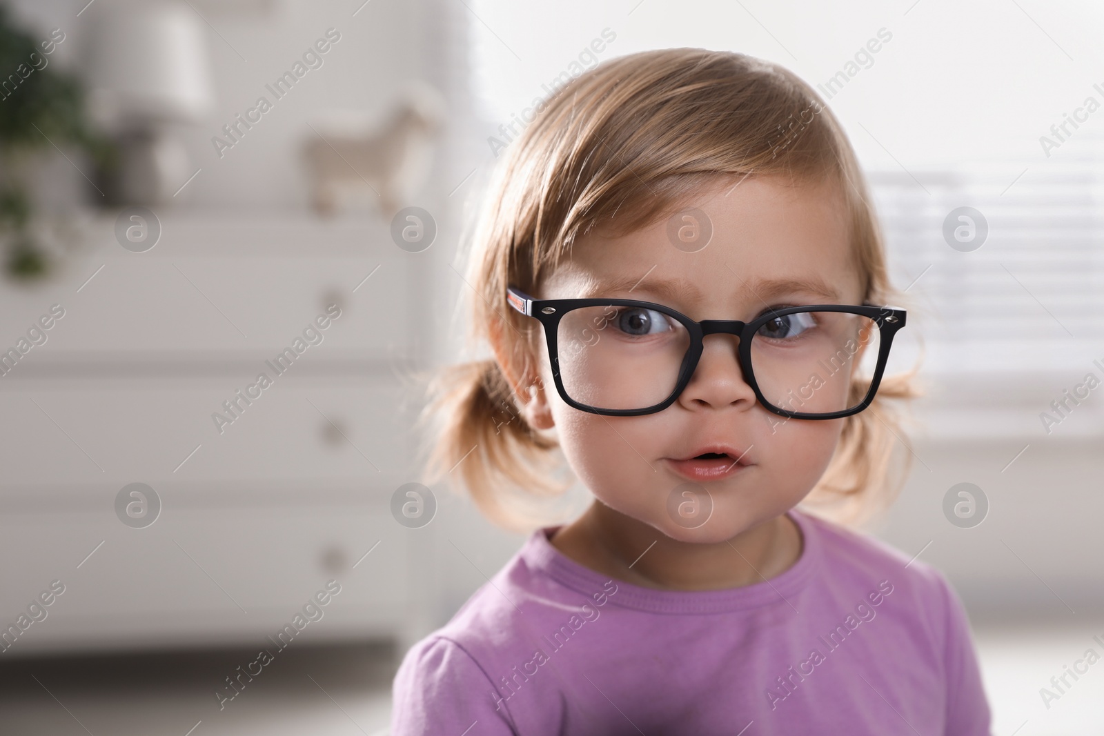 Photo of Cute little girl in glasses at home. Space for text