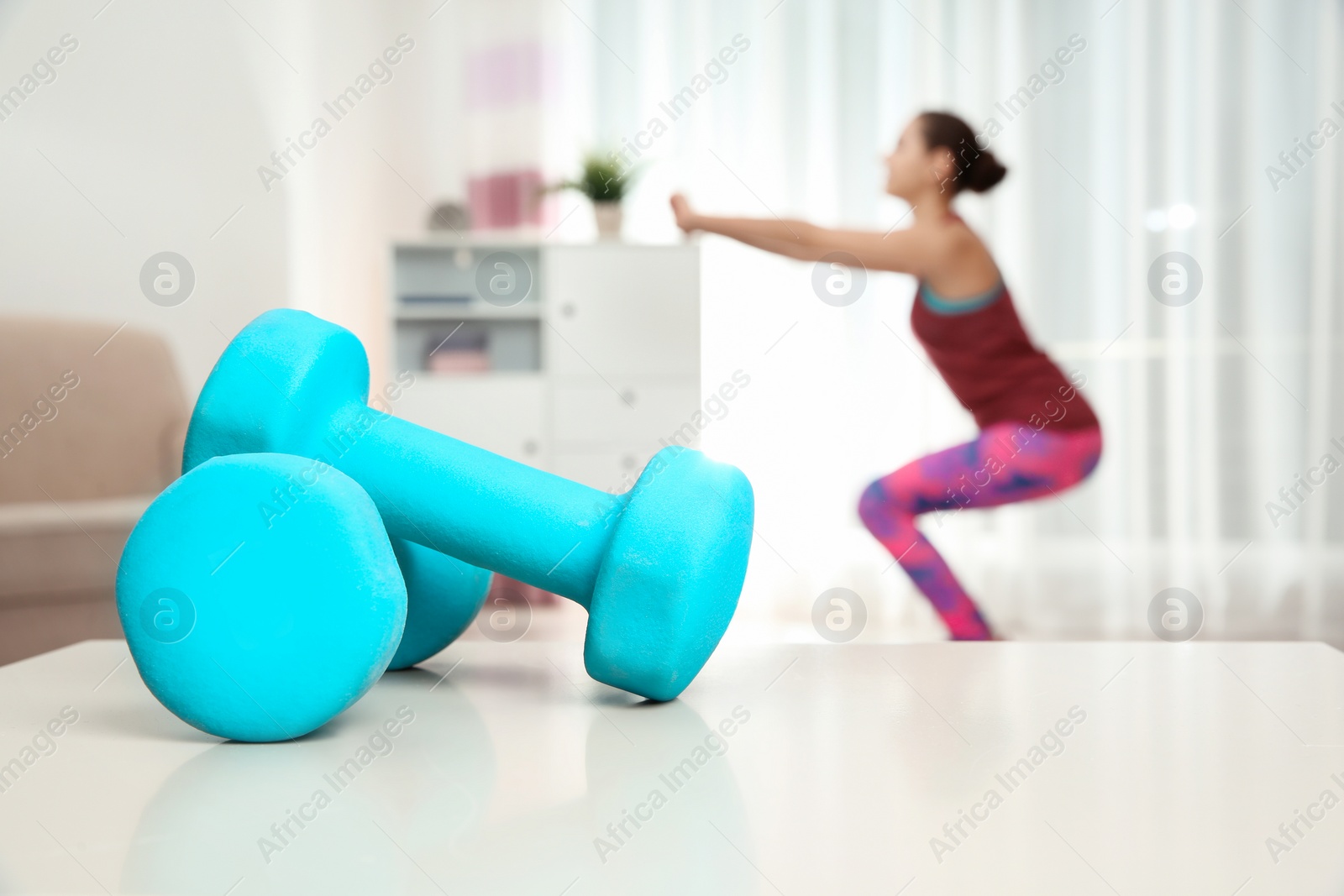 Photo of Woman doing fitness exercise at home, focus on dumbbells. Space for text