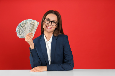 Photo of Young woman with money at table on crimson background