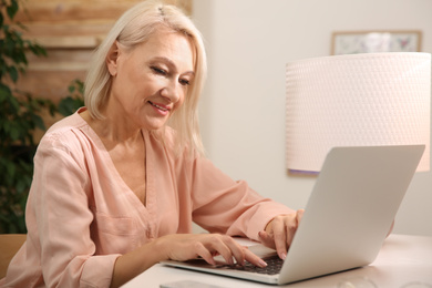 Photo of Beautiful mature woman working with laptop at home