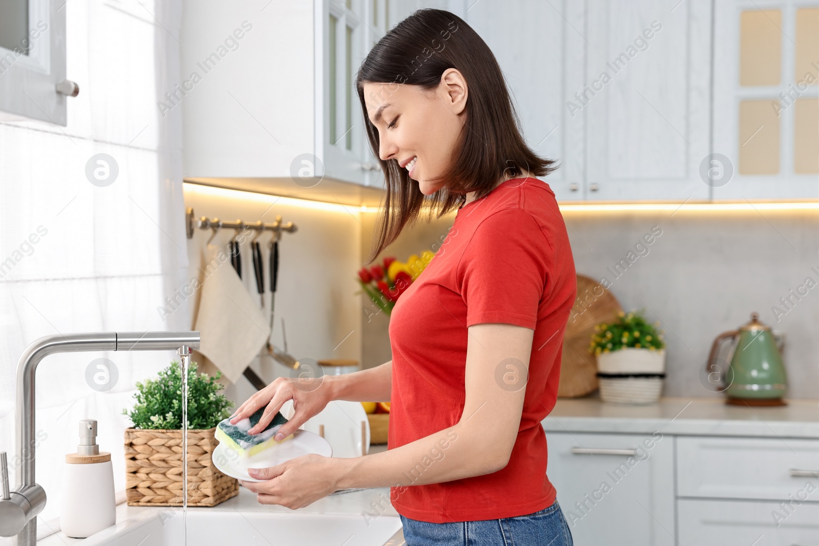 Photo of Woman washing dishes in kitchen sink. Cleaning chores