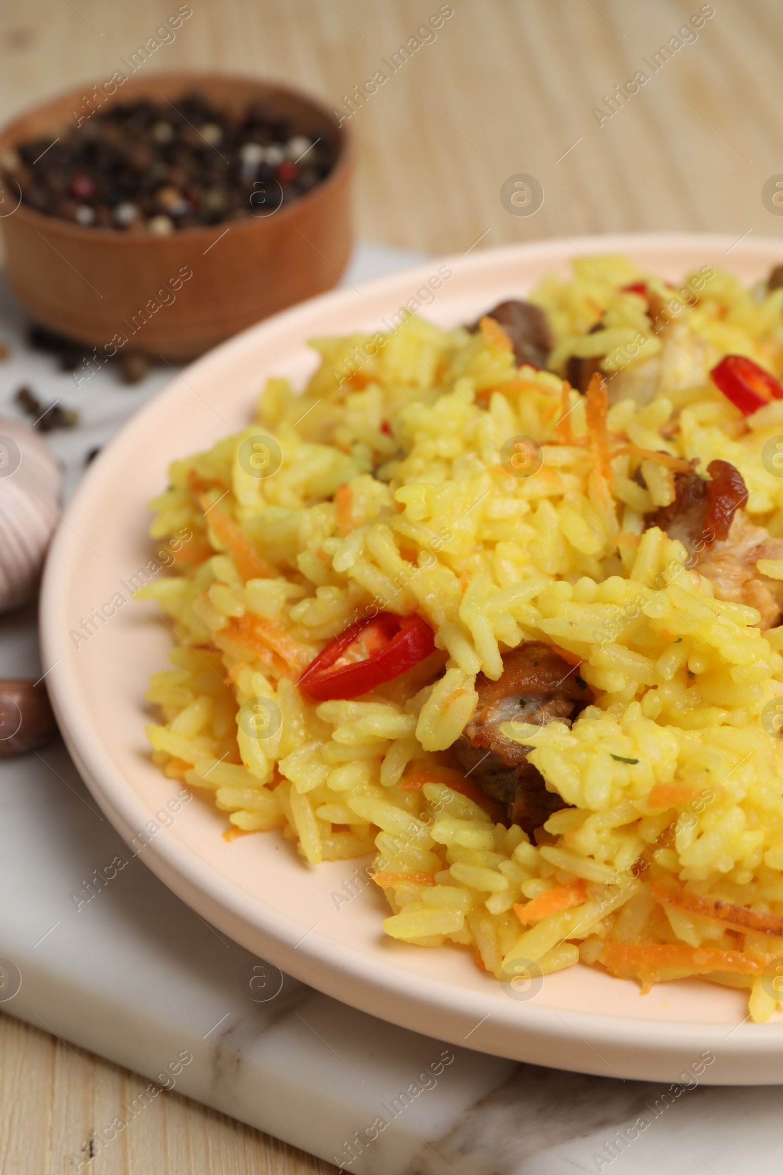 Photo of Delicious pilaf with meat and chili pepper on wooden table, closeup