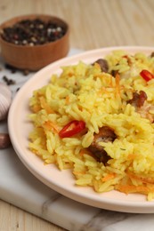 Delicious pilaf with meat and chili pepper on wooden table, closeup