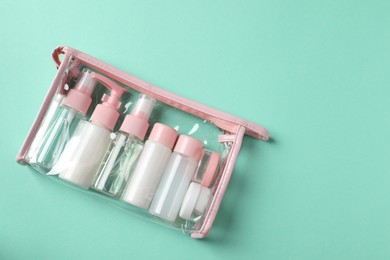 Photo of Cosmetic travel kit in plastic bag on turquoise background, top view. Space for text