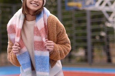 Photo of Woman in warm scarf outdoors, closeup. Space for text