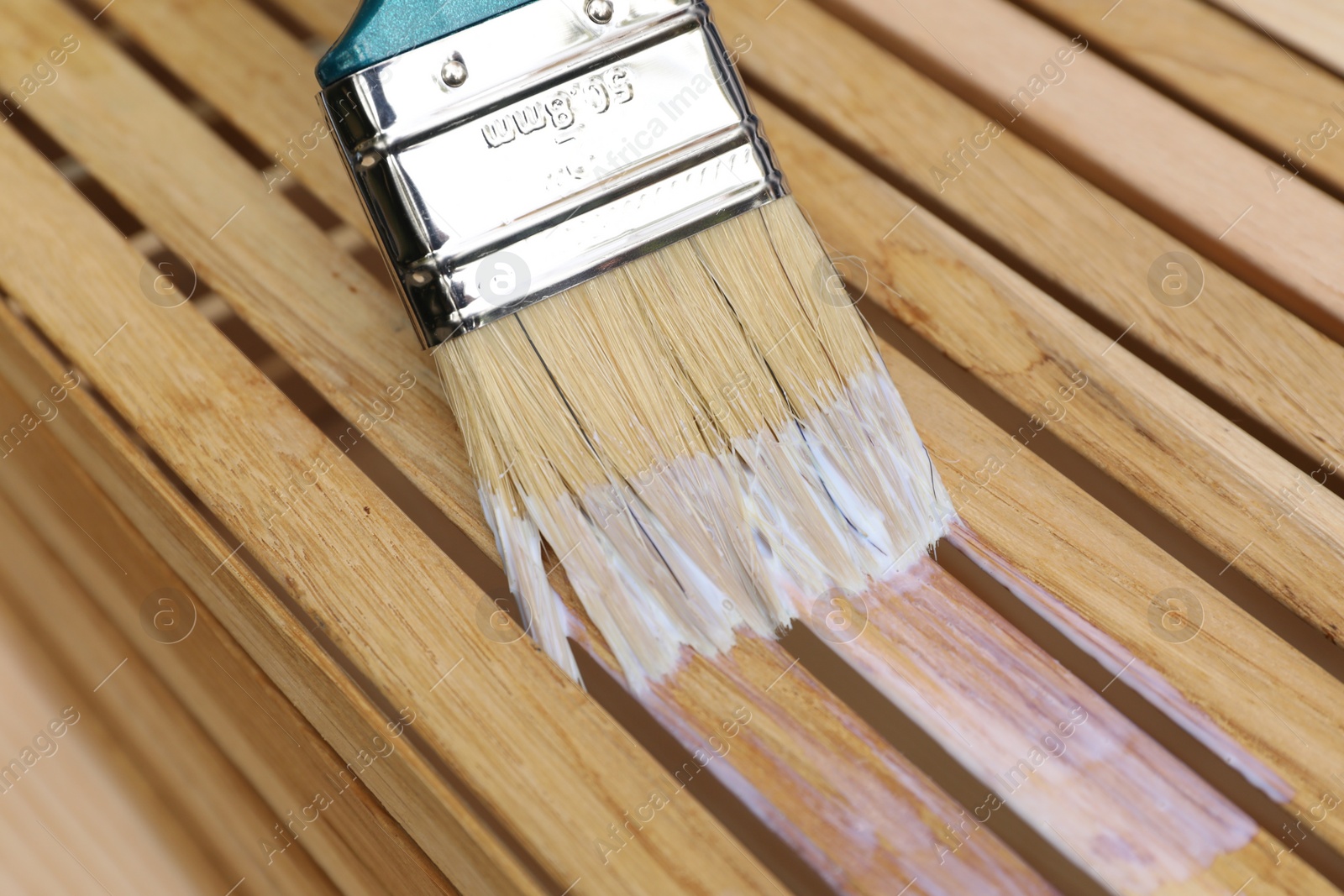 Photo of Applying varnish onto wooden crate with brush, closeup view