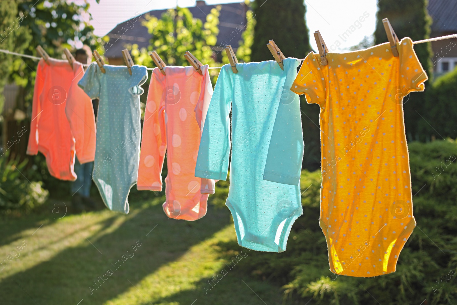 Photo of Baby bodysuits drying on washing line outdoors