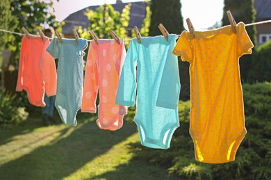 Baby bodysuits drying on washing line outdoors