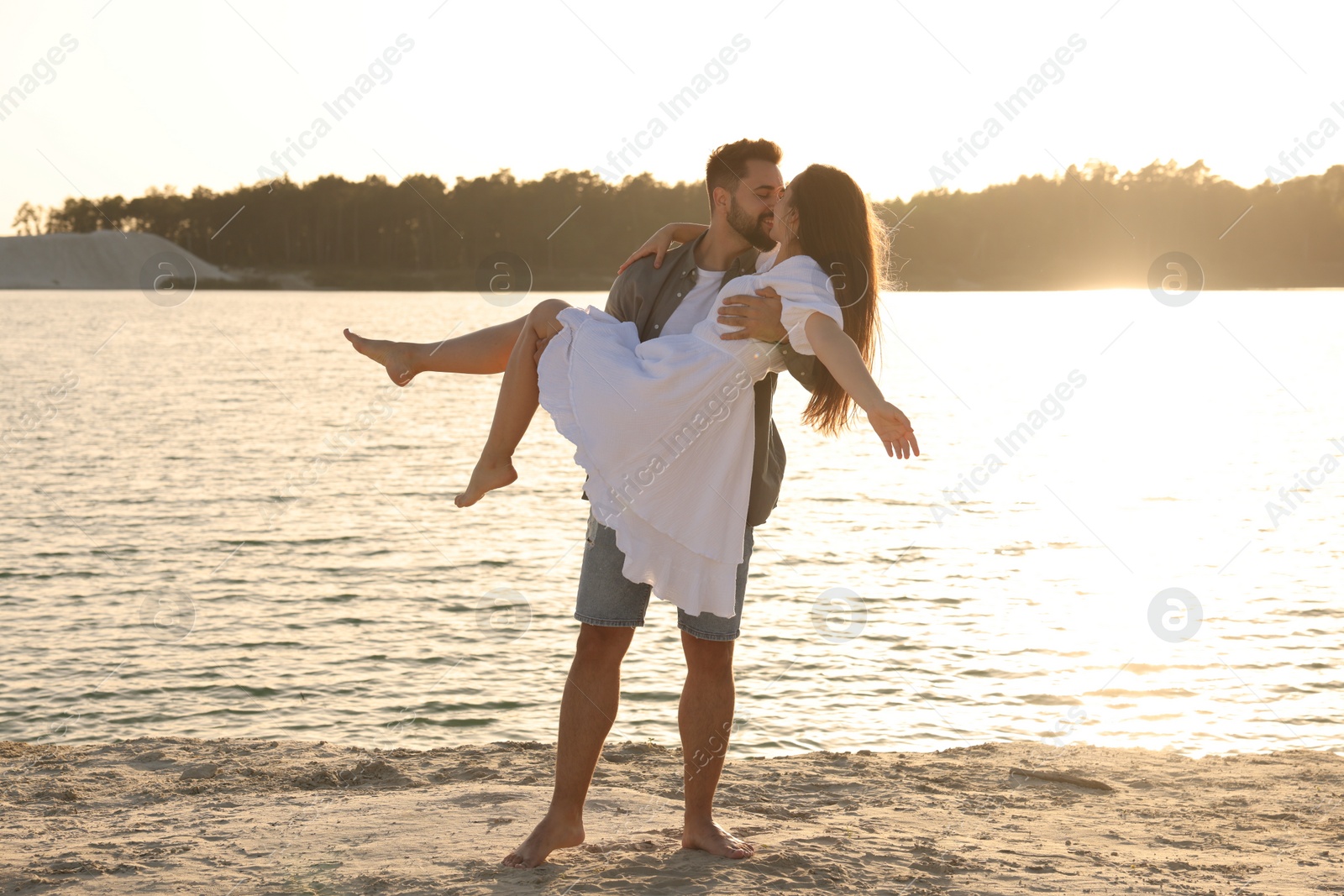 Photo of Beautiful couple dancing and kissing near river on sunny day