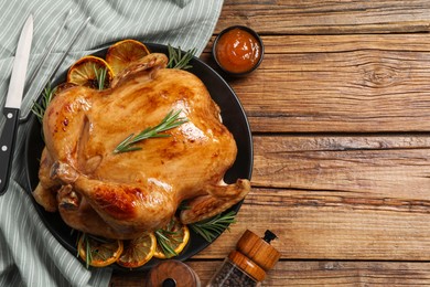 Photo of Tasty roasted chicken with rosemary and lemon served on wooden table, flat lay. Space for text