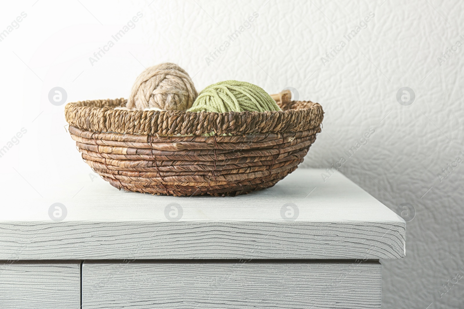 Photo of Wicker basket with knitting threads on table