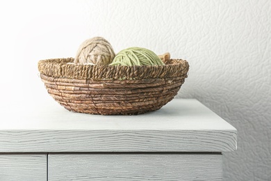 Wicker basket with knitting threads on table