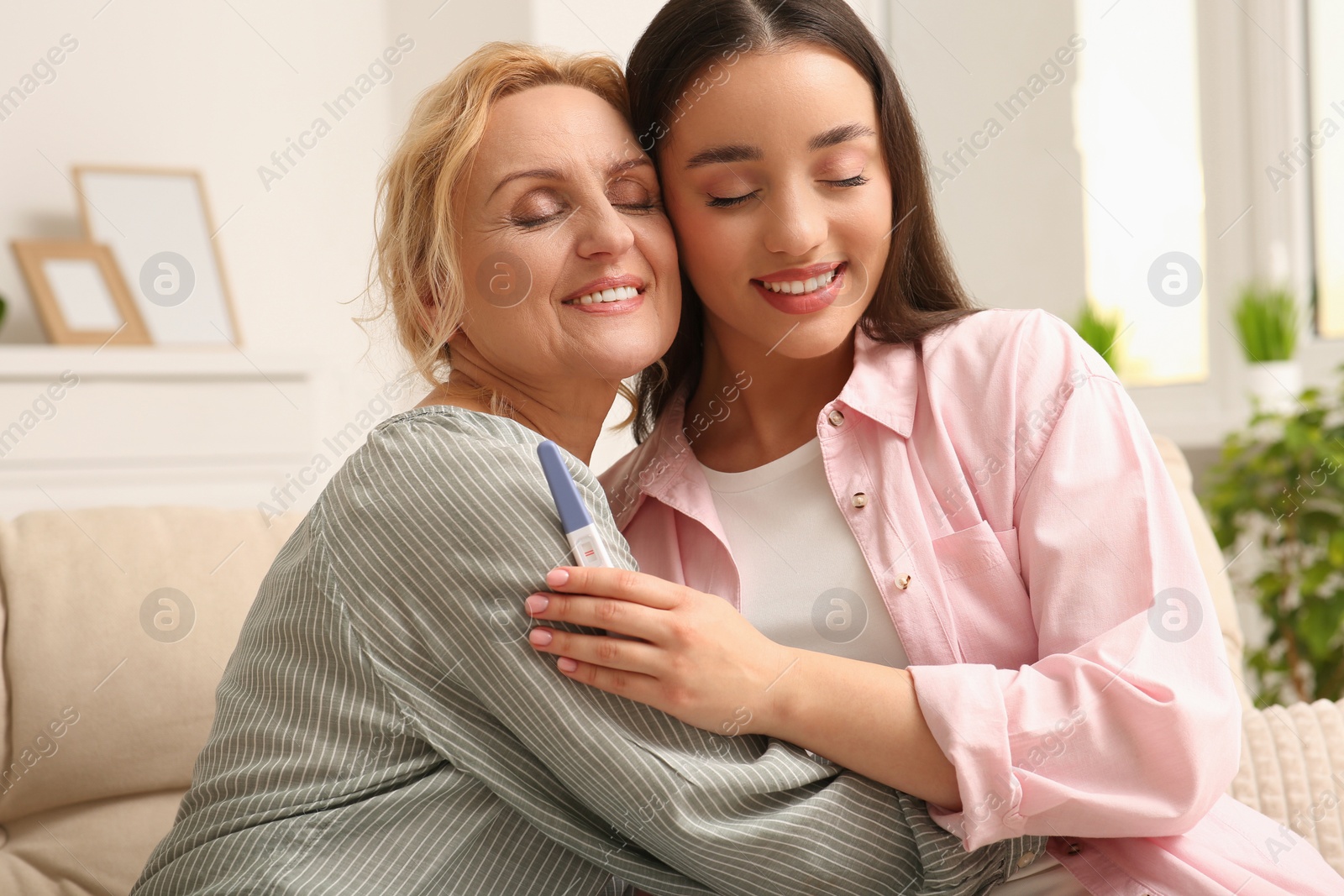 Photo of Happy pregnant woman spending time with her mother at home. Grandparents' reaction to future grandson