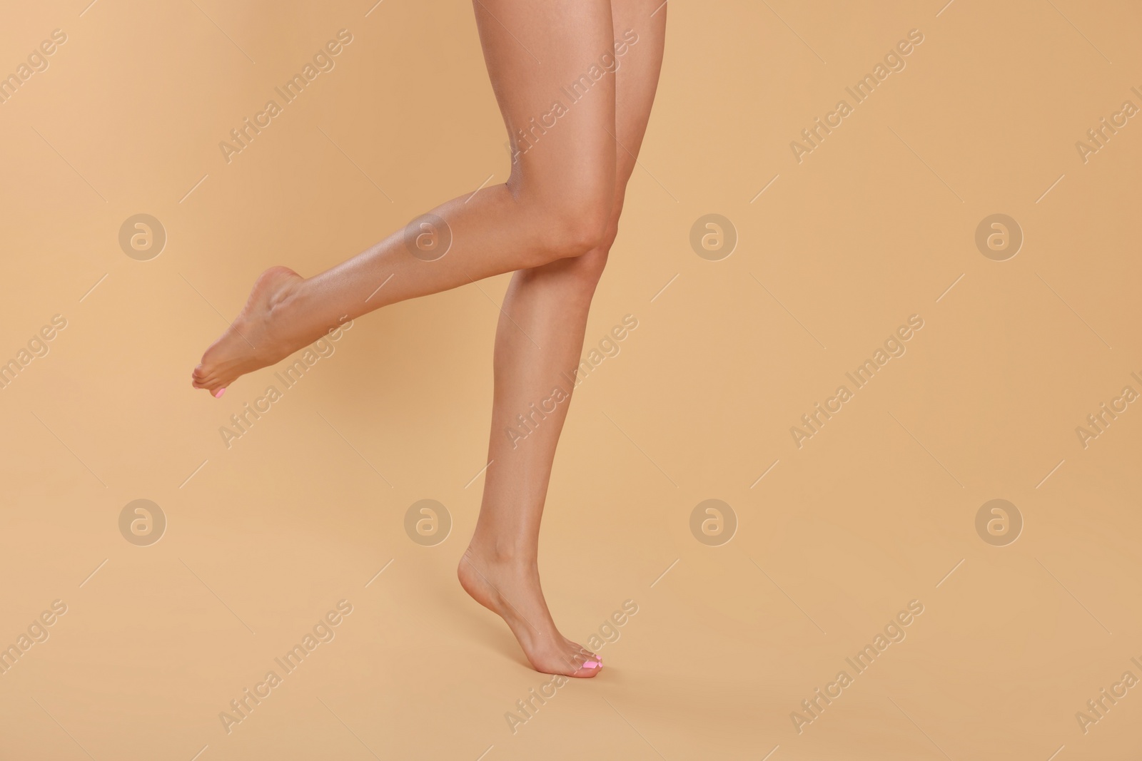 Photo of Woman with beautiful long legs on beige background, closeup