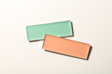 Different color correcting concealers on white background, top view