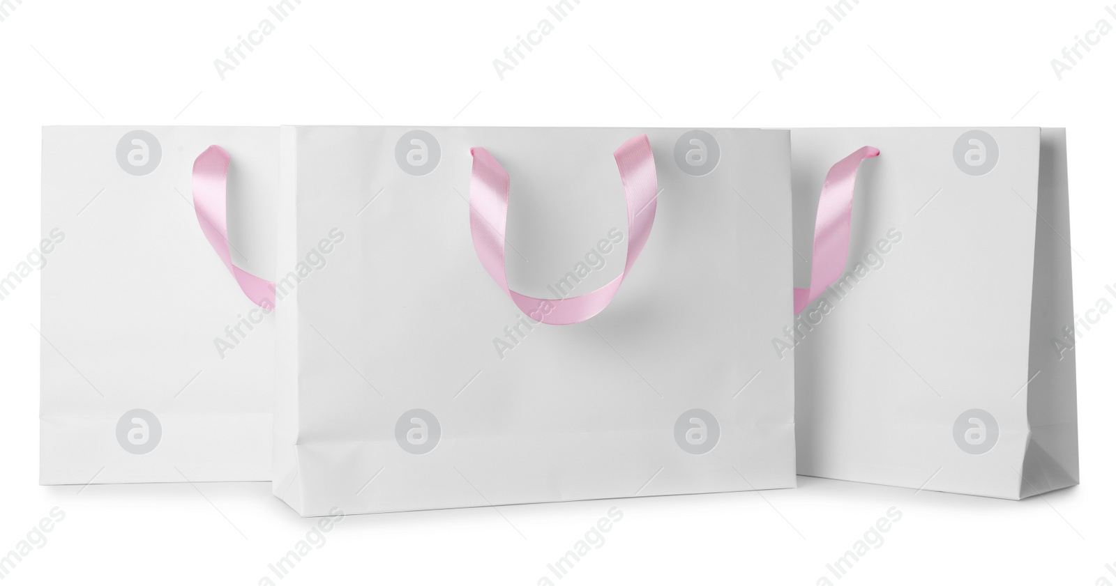 Photo of Paper shopping bags with ribbon handles on white background. Mockup for design